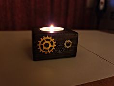 a lit candle sitting on top of a wooden block with gears and cogs in it