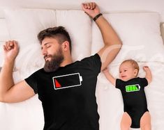 a man laying on top of a bed next to a baby in a black shirt