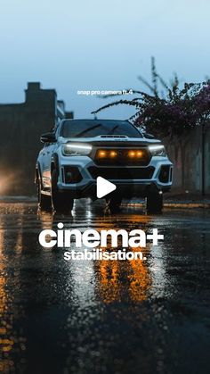 a white car driving down a wet street next to a tall brick building with the words cinema - stabilised on it