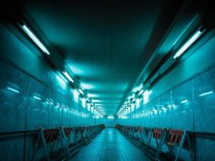 an empty subway tunnel with lights on the ceiling and railings to the left side