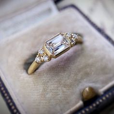 an engagement ring in a box with stones on the bottom and side, sitting on top of it