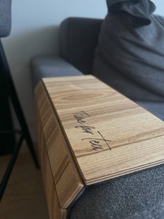 a wooden box sitting on top of a couch next to a gray chair with writing on it