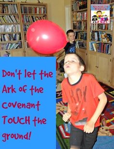 a young boy standing next to a red balloon in front of a blue sign that says, don't let the ark of the covenant touch the ground