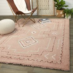 a pink rug with an ornate design on the floor and a chair next to it