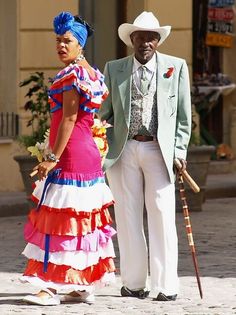 a man and woman dressed in colorful clothing standing next to each other on the street