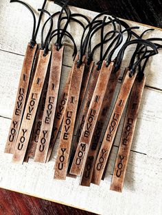 six wooden tags with words on them are hanging from black string and have strings attached to them