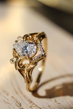 a gold ring with a white diamond in the center on top of a wooden table