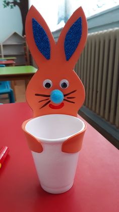 a paper cup with a bunny face on it and a straw in front of it