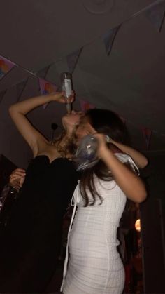 two women standing next to each other in front of a party flag and holding drinks