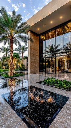 a large glass building with palm trees in the front yard and landscaping on both sides