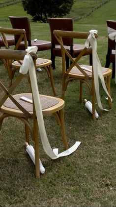 several wooden chairs with white ribbons tied to them