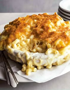 a white plate topped with macaroni and cheese covered in gravy next to silverware