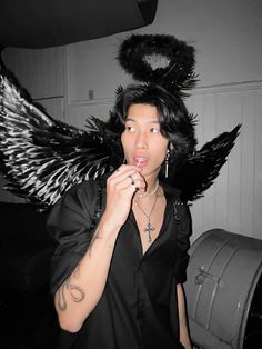 a woman with black hair and angel wings on her head brushing her teeth in front of a mirror