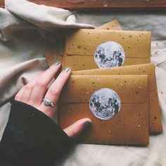 a woman's hand holding two envelopes with the moon and stars on them