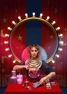 a woman with long hair is standing in front of a red table holding a glass ball