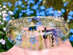 This gorgeous handmade bangle has real plants inside - fern and Forget-Me-Not. Fern is one of the most ancient species, it contains deep wisdom of Mother Earth in its graceful fronds. It symbolises family, new beginnings, hope for new generations, sincerity. Forget Me Not is a very sweet and special flower. It means true and undying love, remembrance, a connection that lasts through time. Forget Me Nots are reminders of your favorite memories together with someone dear. OVERVIEW ✿ The bracelet i Deep Wisdom, Lucite Bracelets, Undying Love, Resin Bangles, Mother Jewelry, Special Flowers, Eco Resin, Forget Me Nots, Handmade Bangles