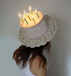 a woman wearing a birthday cake hat with lit candles