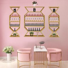 two pink chairs sitting next to a table in front of a wall mounted wine rack