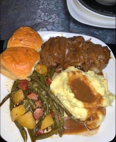 a white plate topped with meat, potatoes and green beans