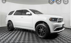 a white dodge truck is parked in a room with black and white checkered flooring