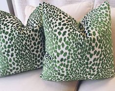 two green and white pillows sitting on top of a couch