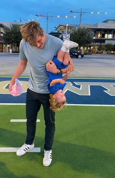 a man holding a small child on top of his head while standing on a field