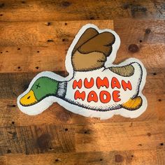 a sticker with the words human made on it sitting on a wooden floor next to a wall