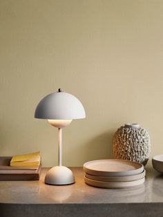 a table topped with plates and a white lamp next to a bowl on top of a counter