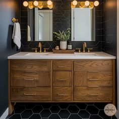 a bathroom with two sinks, mirrors and lights on the wall above it's counter