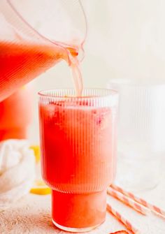 a pitcher pouring liquid into a glass with straws