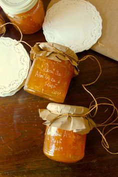 three jars filled with honey sitting on top of a wooden table next to doily