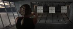 a woman taking a photo of some target shooting in a room with glass walls and floor