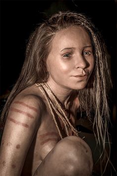 a woman with long hair and tattoos on her body is posing for a photo in the dark