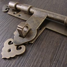 a close up of an old style door hinge on a wooden surface with metal latches