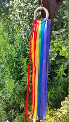 a wind chime hanging from the side of a wooden pole in front of some bushes