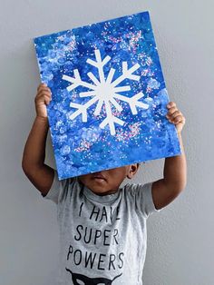 a young boy holding up a paper snowflake on top of his head with the words i have super powers written on it