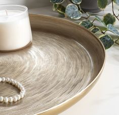 a candle sits on a tray next to a beaded bracelet and a glass of milk