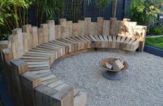 a circular bench made out of wooden planks in a gravel area with a fire pit