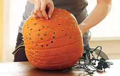 a person is holding an orange pumpkin with holes on it