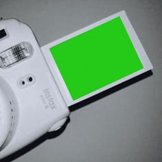 a white camera with a green screen attached to it's back cover on a table