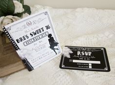 a wedding card and ticket sitting on top of a white lace covered blanket next to a bouquet of flowers