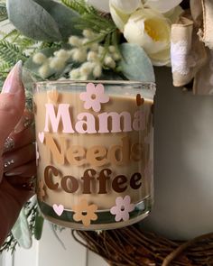 a hand holding a glass jar filled with coffee and marshmallows on the side