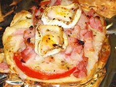 a pizza with ham, cheese and tomatoes on it sitting on top of some bread