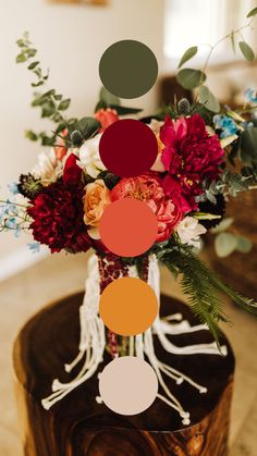 a vase filled with lots of flowers on top of a wooden table covered in greenery