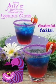 two glasses filled with blue liquid and strawberries sitting on top of a purple plate