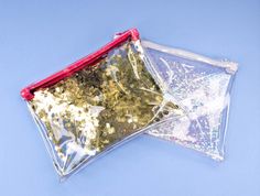 two bags filled with gold flakes on top of a blue surface