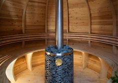 the inside of a wooden building with a metal pole and circular seating area in front of it