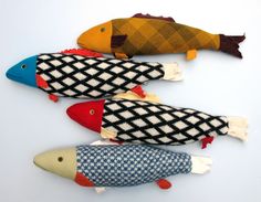 three fish made out of fabric sitting on top of a white surface with red, yellow and blue colors