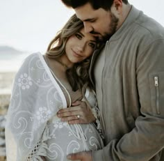 a man and woman embracing each other on the beach