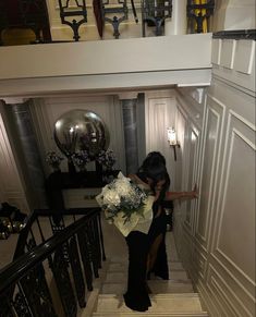 a woman is walking down the stairs with flowers in her hand